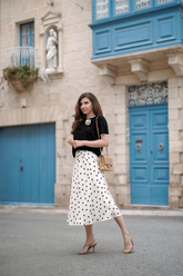 a lady in a black top and a white skirt with black polka dots